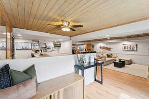 Living room with recessed lighting, light wood finished floors, wooden ceiling, and a ceiling fan
