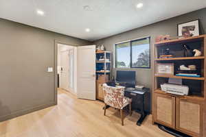 Home office with light wood-type flooring, a textured ceiling, and recessed lighting