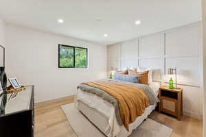 Bedroom featuring a decorative wall, light wood-type flooring, and recessed lighting