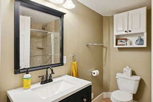 Full bath with vanity, a textured ceiling, and a tile shower