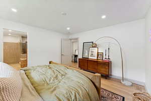Bedroom featuring light wood-style floors, recessed lighting, ensuite bath, and a textured ceiling