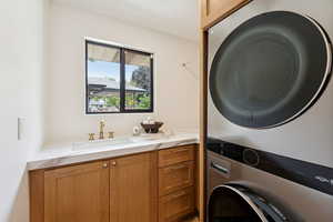 Laundry room with estacked washer and dryer and a sink