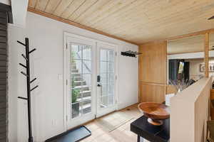 Doorway to outside featuring stairs, wood finished floors, wooden ceiling, ornamental molding, and french doors
