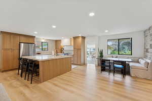 Kitchen featuring open floor plan, a kitchen island with sink, a breakfast bar area, recessed lighting, and light wood-type flooring