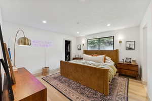 Bedroom featuring recessed lighting, a walk in closet, light wood finished floors, a textured ceiling, and washer / clothes dryer