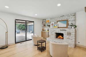 Living area featuring light wood finished floors, a stone fireplace, and recessed lighting
