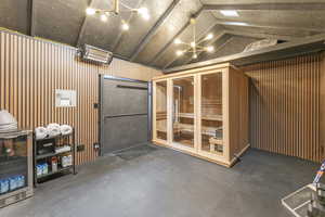 Garage featuring a relaxing sauna, wooden walls, and wine cooler