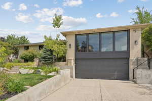 View of front of house with concrete driveway, brick siding, stairs, and an attached garage