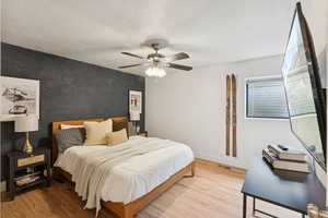 Bedroom featuring light wood-style floors, a ceiling fan, and a textured ceiling