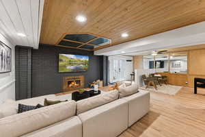 Living area with brick wall, wood finished floors, wood ceiling, a fireplace, and recessed lighting