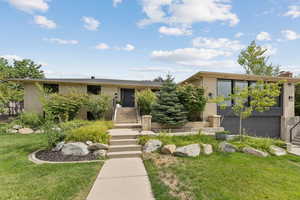 View of front facade featuring brick siding, a front yard, a garage, and stairs