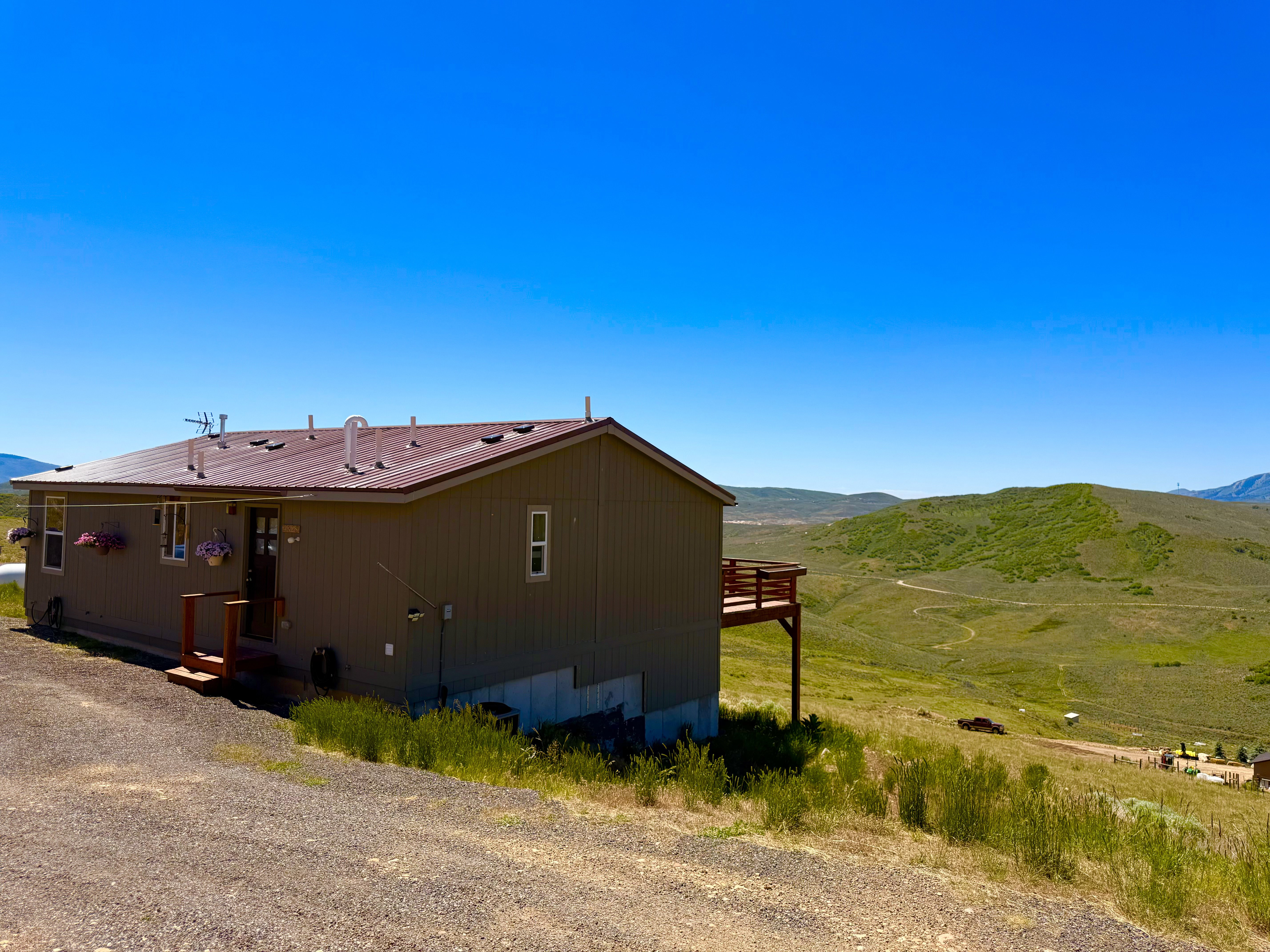 Property exterior featuring a brown metal roof and siding, a front entry with a small porch, and a rear deck