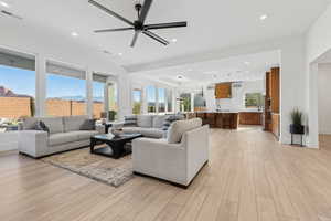 Living area with a mountain view, recessed lighting, light wood-type flooring, ceiling fan, and a tray ceiling