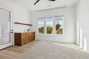 Bar featuring brown cabinets, open shelves, a ceiling fan, modern cabinets, and light wood finished floors