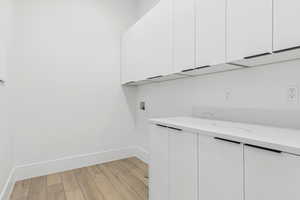Laundry area with light wood-style floors, cabinet space, and hookup for a washing machine