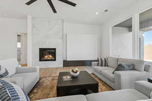 Living room with wood finished floors, a high end fireplace, ceiling fan, and recessed lighting