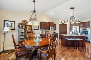 Dining room with dark wood-type flooring, lofted ceiling, recessed lighting, and a chandelier