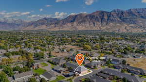 Aerial view of property and surrounding area featuring mountains and nearby suburban area