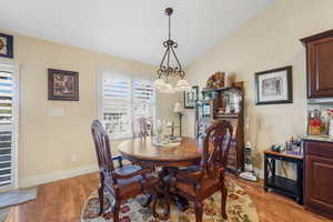 Dining space featuring light wood-style floors, vaulted ceiling, and a chandelier