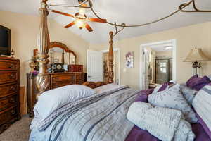 Carpeted bedroom featuring lofted ceiling, a ceiling fan, and connected bathroom