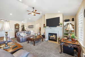 Living area featuring a glass covered fireplace, carpet flooring, arched walkways, a ceiling fan, and recessed lighting