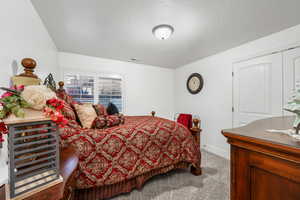 Carpeted bedroom featuring a textured ceiling and baseboards