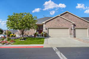 Ranch-style home featuring driveway, brick siding, a garage, and a front yard
