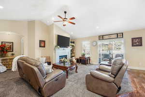 Living area with recessed lighting, a lit fireplace, a ceiling fan, wood finished floors, and high vaulted ceiling