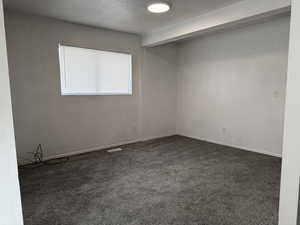 Spare room featuring dark colored carpet and a textured ceiling