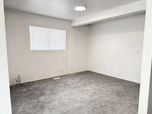 Carpeted spare room with a textured ceiling and baseboards
