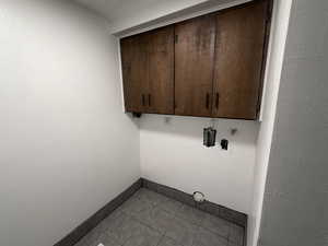 Laundry area with hookup for a washing machine, cabinet space, and light tile patterned floors