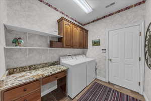 Laundry room featuring cabinet space, washer and dryer, and wallpapered walls