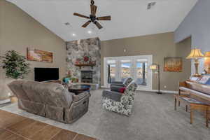Carpeted living room with high vaulted ceiling, a fireplace, ceiling fan, and recessed lighting