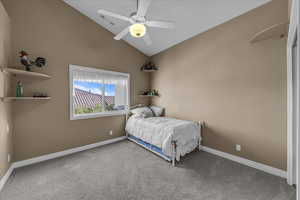 Carpeted bedroom with a ceiling fan and high vaulted ceiling