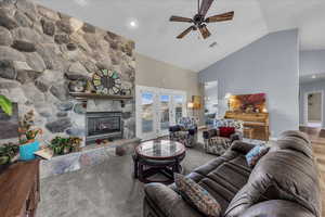 Living area with high vaulted ceiling, french doors, a stone fireplace, ceiling fan, and recessed lighting