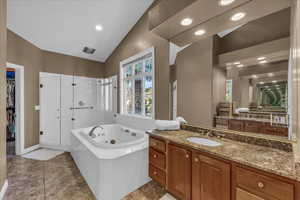 Bathroom with a whirlpool tub, vanity, a spacious closet, recessed lighting, and a stall shower