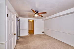 Unfurnished bedroom featuring light carpet, a ceiling fan, and a textured ceiling