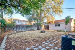 Fenced backyard with a fire pit, an outdoor structure, and a patio area