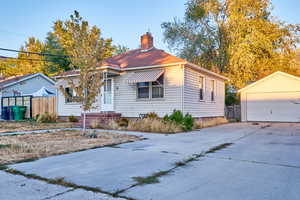Bungalow-style house featuring an outbuilding, a garage, and a chimney