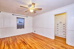 Empty room featuring ornamental molding, light wood-style flooring, and a ceiling fan