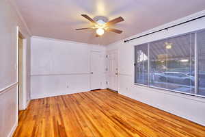 Unfurnished room with light wood finished floors, crown molding, and a ceiling fan