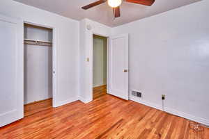 Unfurnished bedroom featuring light wood-style flooring, ceiling fan, and a closet