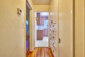 Corridor featuring light wood-style floors and a textured wall
