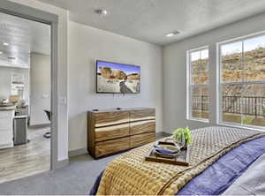 Bedroom featuring light colored carpet and a textured ceiling