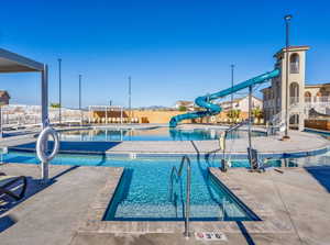 Community pool featuring a water slide and a patio