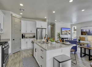 Kitchen with light stone counters, white cabinetry, wood finish floors, stainless steel appliances, and recessed lighting