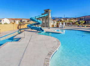 Community pool featuring a water slide, a patio, and a residential view