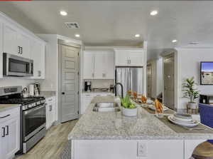 Kitchen with stainless steel appliances, white cabinetry, light stone counters, recessed lighting, and wood tiled floors