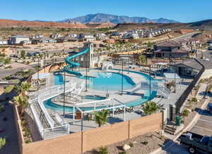 Community pool with a water slide, a residential view, a mountain view, and a patio area