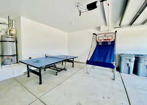 Game room with a garage, secured water heater, and concrete flooring